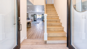 Bright, modern entryway of a Newport Beach home listed by Kevin P. Smith, featuring wood flooring, open stairway, and a view into the living area.