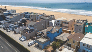 Aerial view of Surfside beachfront homes in California, highlighting a blue home listed by Angela Caliger with direct beach access and expansive ocean views.