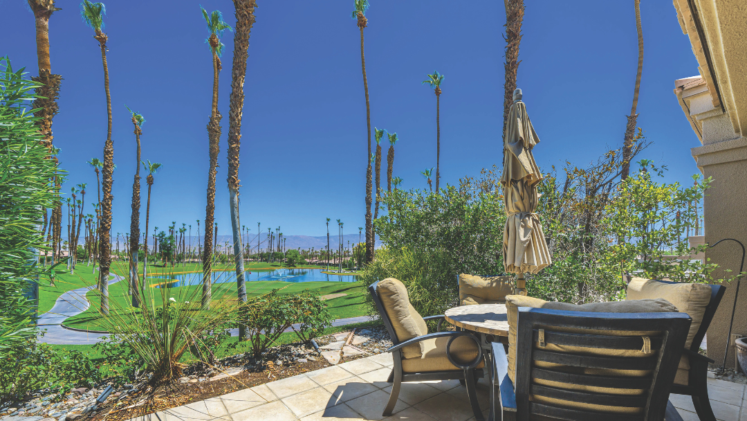 Outdoor patio with seating overlooking lush golf course, palm trees, and mountain views in Palm Desert home listed by Max Caliger.