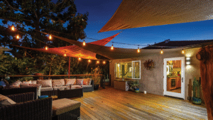 Stylish backyard patio with string lights, outdoor sectional seating, and shade sails at twilight in Costa Mesa home.