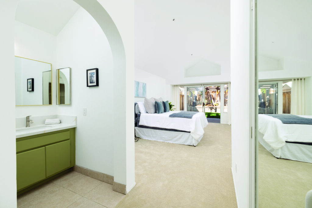 Primary bedroom suite in a Yorba Linda home featuring a vanity area, vaulted ceilings, and sliding glass doors opening to a private backyard, listed by DeAnne Amen.