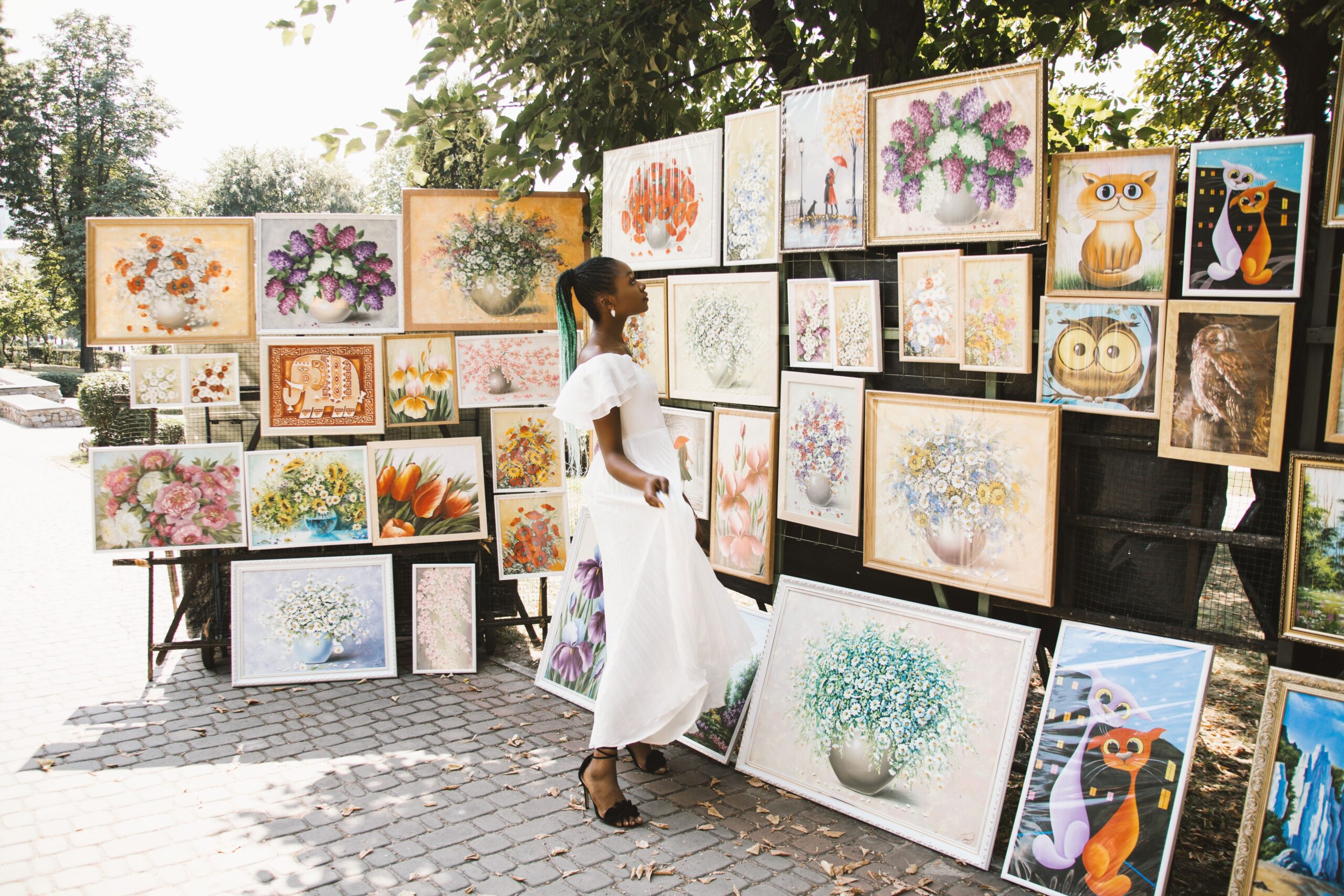 Woman browsing colorful artwork at an outdoor art festival, representing the Sawdust Art Festival in Laguna Beach, California.