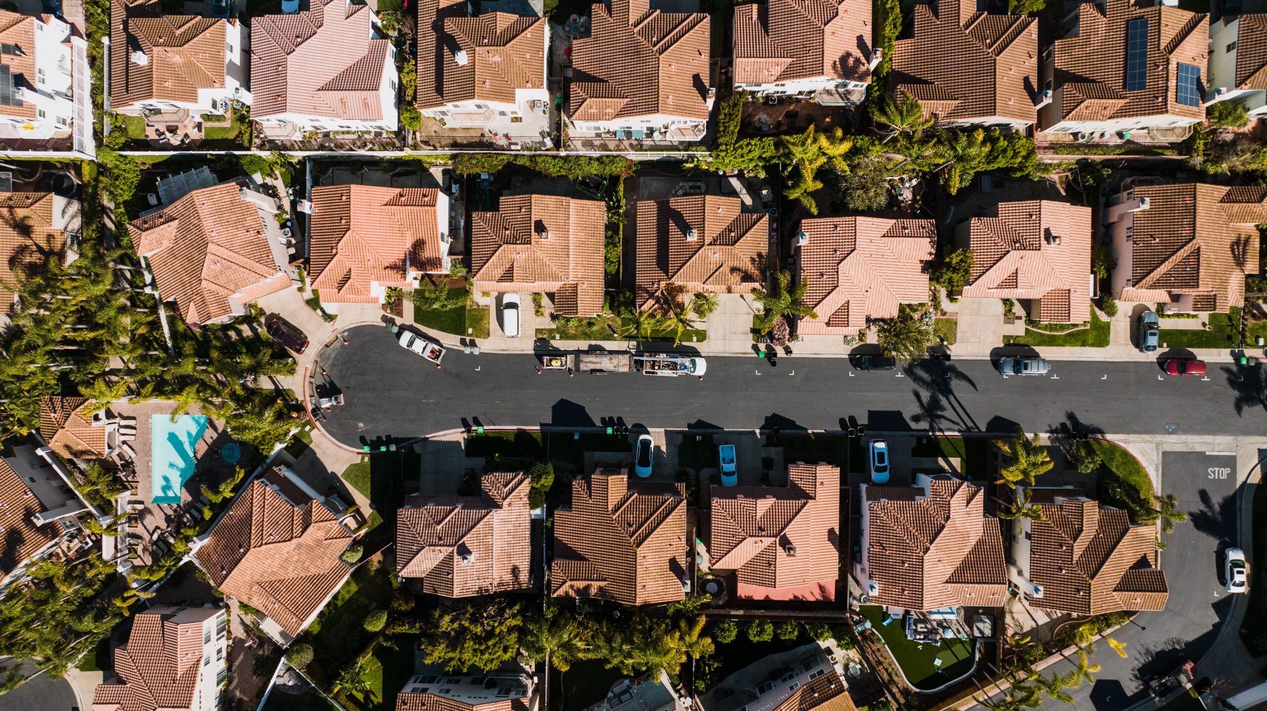 Aerial view of Costa Mesa homes with red tile roofs, palm trees, and residential streets in Orange County, California.
