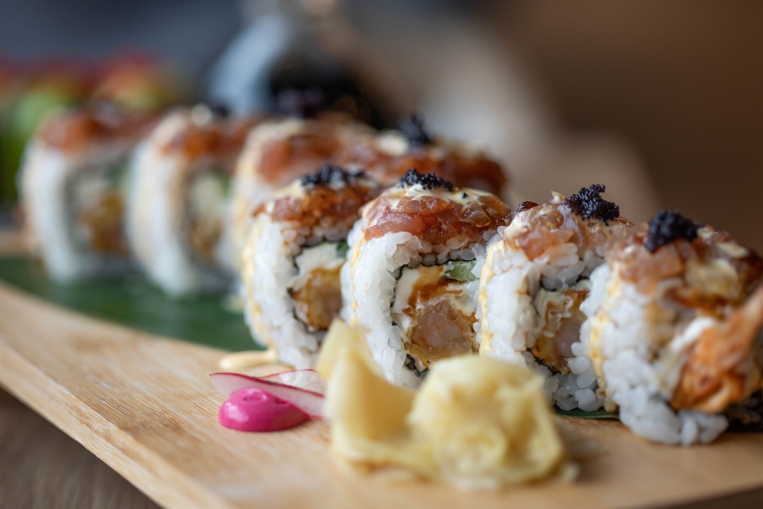 Close-up of delicately hand-crafted nigiri sushi served on a dark ceramic plate at an upscale Orange County restaurant.