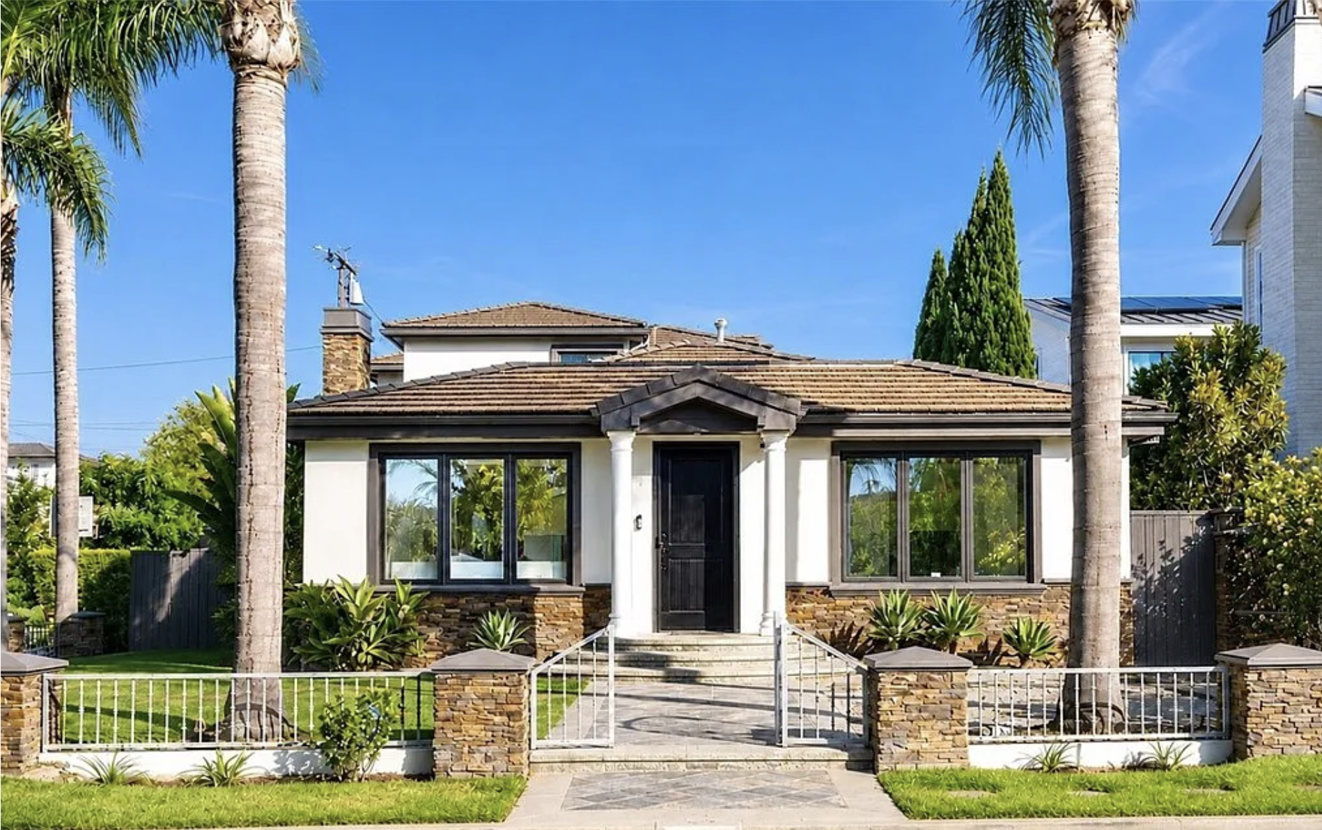 Newport Beach home with palm trees, landscaped front yard, and stone accents, listed by Manny Stellino