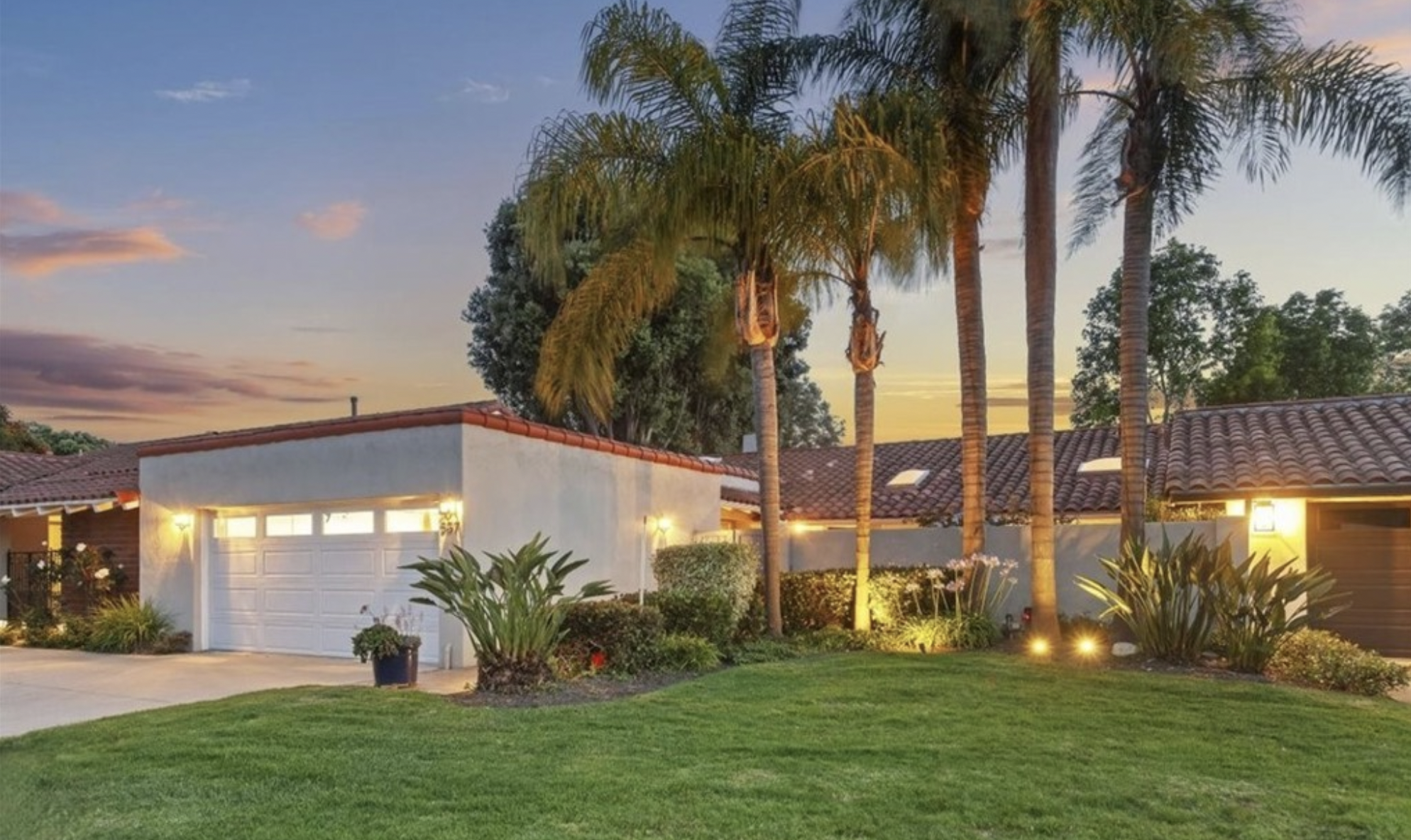 Newport Beach home at sunset with palm trees, manicured lawn, and illuminated landscaping, listed by Kathy Fallon