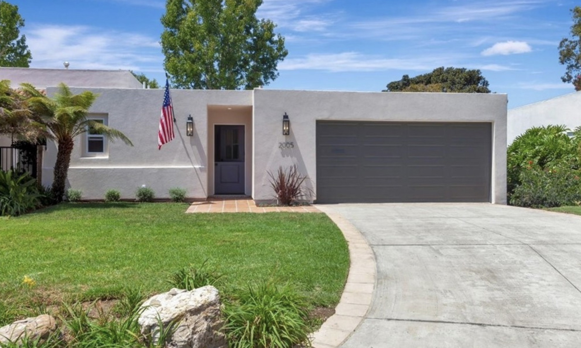 Newport Beach home with a clean modern exterior, manicured lawn, two-car garage, and tropical landscaping, listed by Kathy Fallon