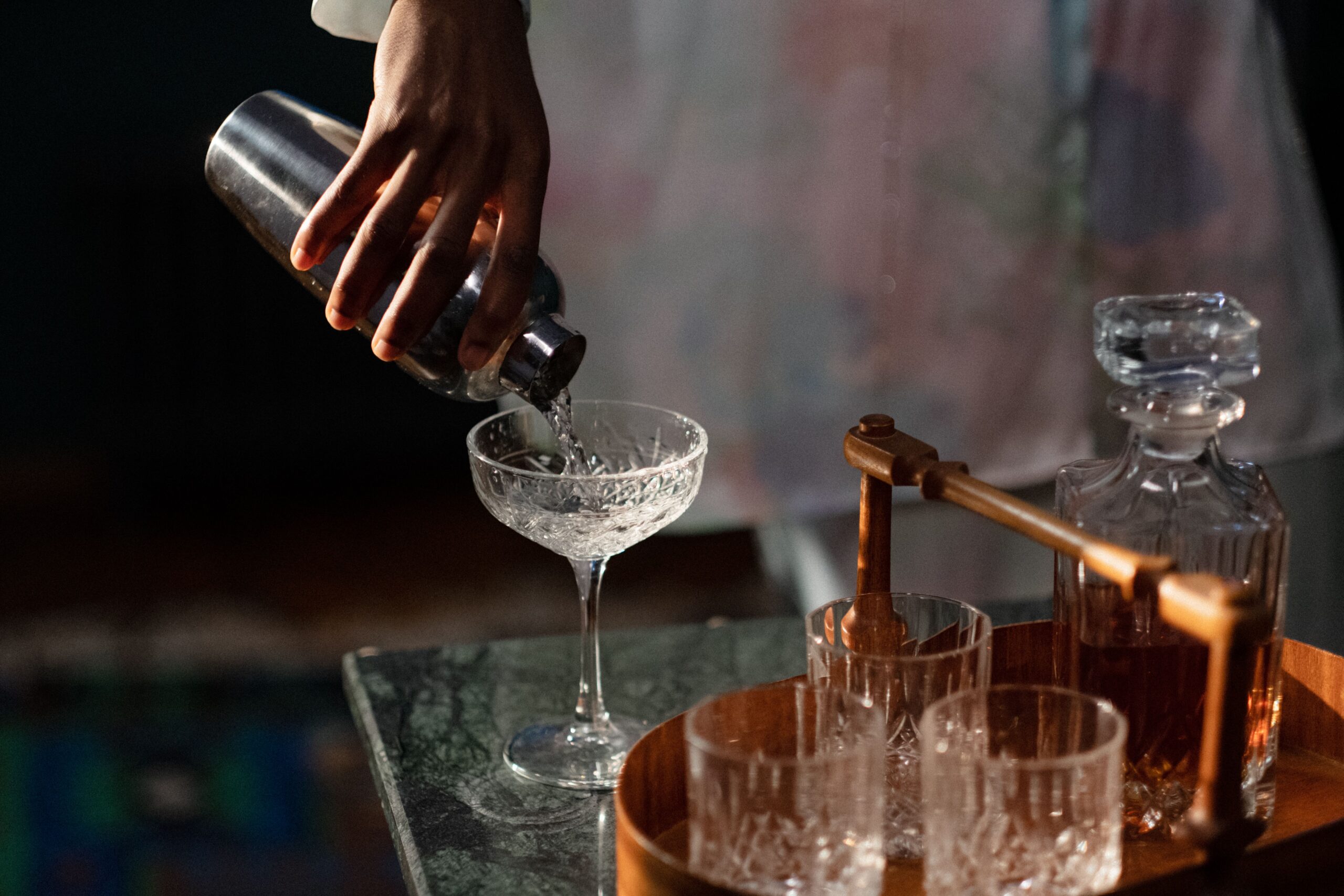Bartender pouring a handcrafted cocktail into a coupe glass at an Orange County speakeasy